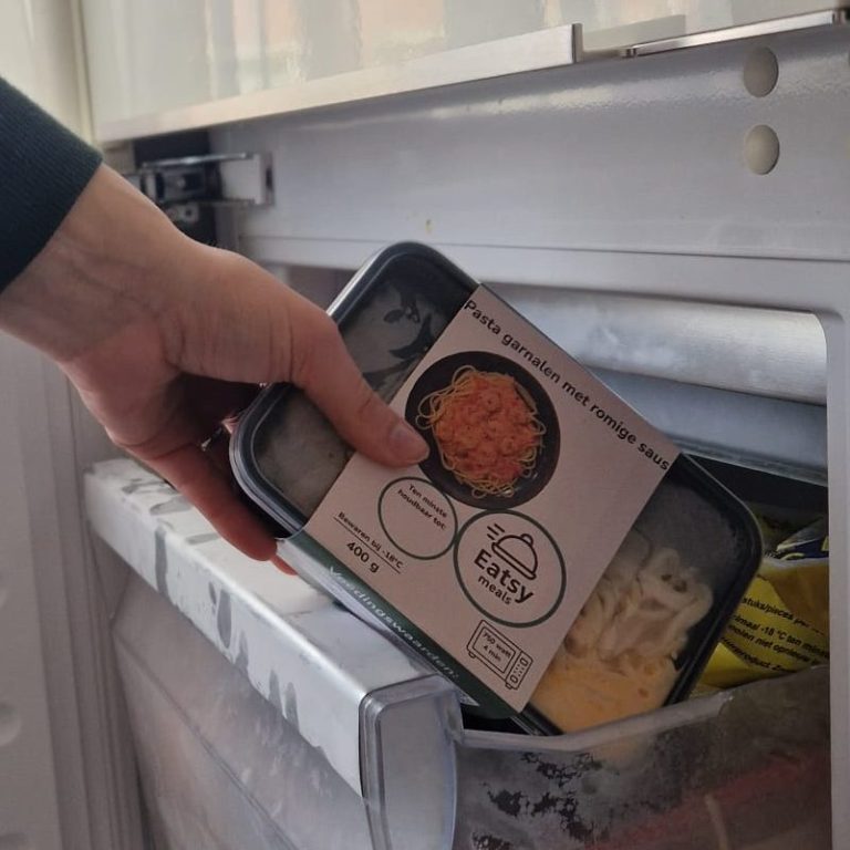 Een hand pakt een maaltijdverpakking uit de vriezer.